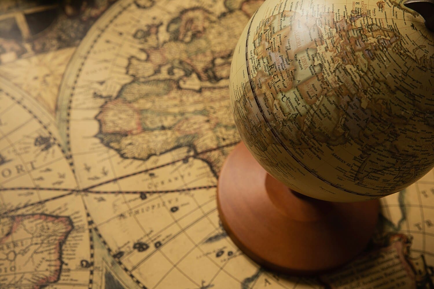 Ein klassischer Globus steht auf einer antiken Weltkarte – symbolisch für die authentischen Entdeckungsreisen nach Thailand und Korea mit den Erlebnisboxen von Oversea Crate.