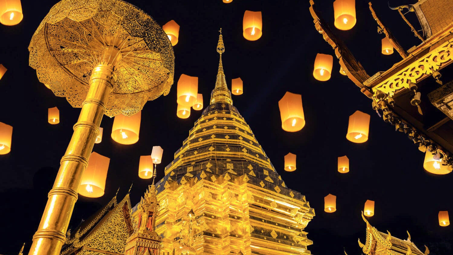 Goldener thailändischer Tempel in der Nacht, umgeben von hunderten leuchtenden Laternen beim Lichterfest in Chiang Mai – erlebe magische Momente mit der Thailand Erlebnisbox von Oversea Crate.